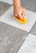 person cleaning tiles and grout with a yellow brush