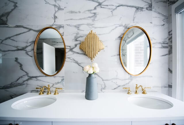 Modern bathroom vanities with marble wall and gold faucets and mirror