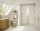 White bathroom with lots of natural light and an all white shower featuring glass door and shower shelves