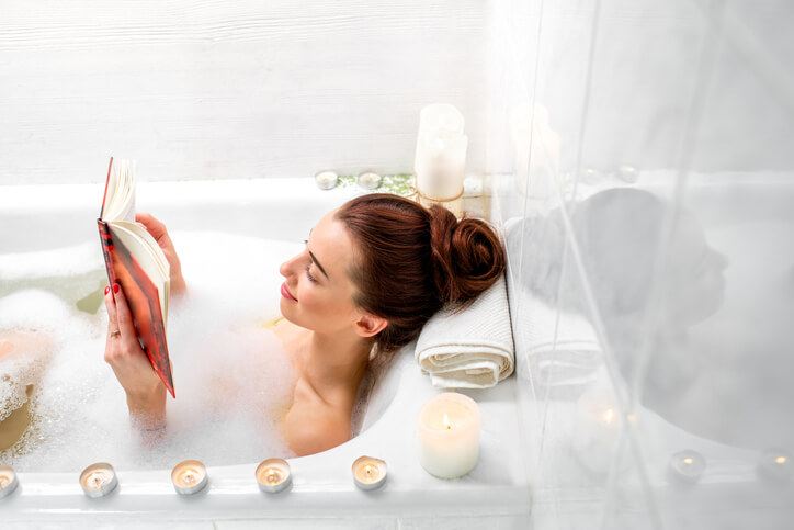 Woman reading a book while relaxing in bath