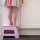 Girl standing on a pink stool