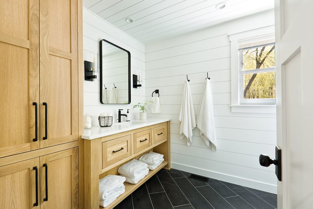 A contemporary cabin bathroom featuring a freestanding vanity and wooden linen closet.