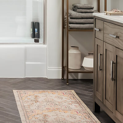 Rug is on herringbone bathroom tile in front of vanity sink