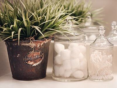 Cotton balls and cotton swabs are on display in clear apothecary jars.