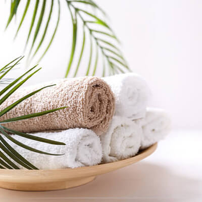 rolled up bathroom towels in a wooden bowl