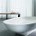 Bathtub on a tiled floor with a two seat bench in the background
